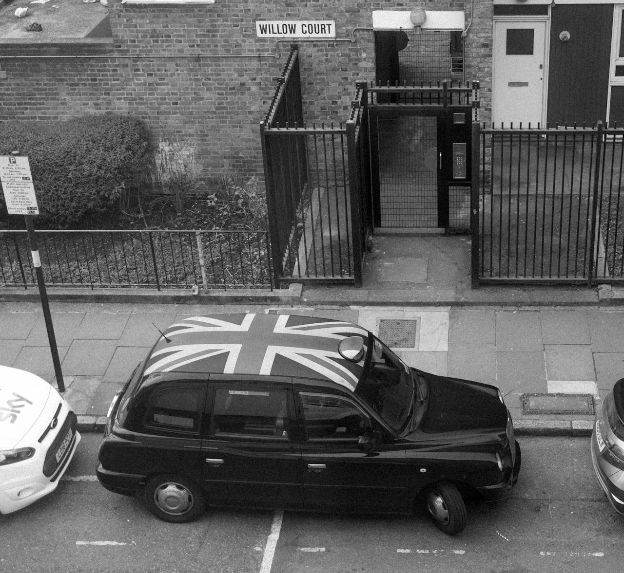 A British taxi adorned with the Union Jack parked on a London street.