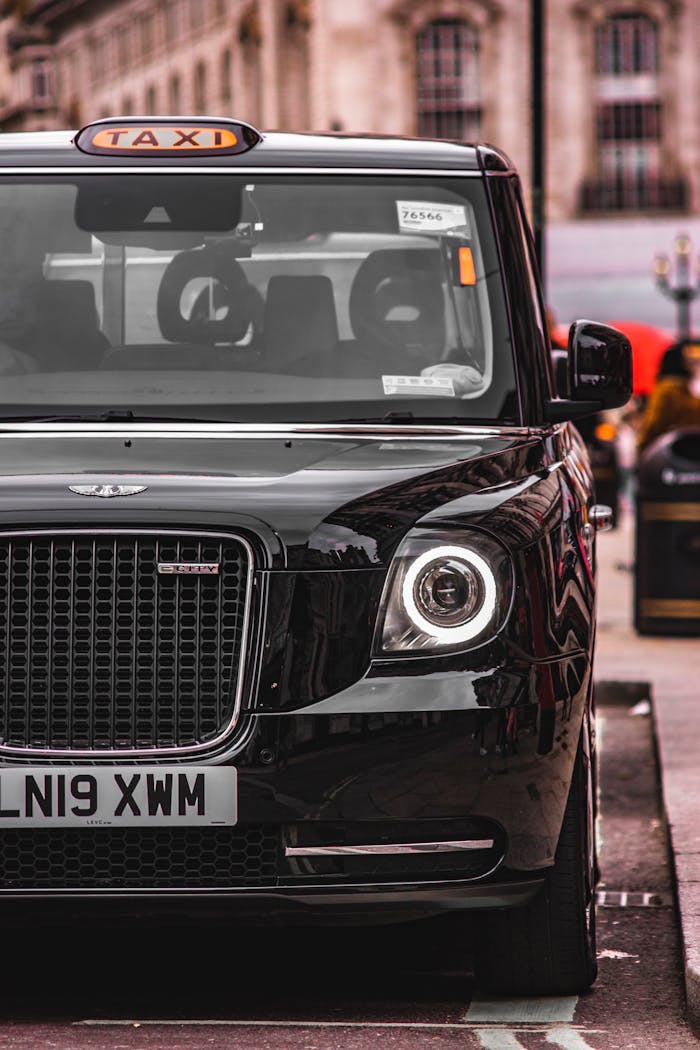 Front view of a classic black taxi parked on a city street highlighting urban elegance.